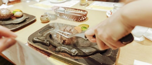 熱々の鉄板にステーキをジューする光景の写真