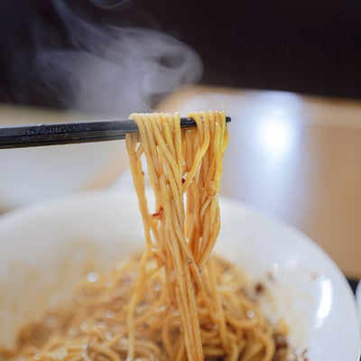 熱々の汁なし担々麺を箸で持ち上げるの写真