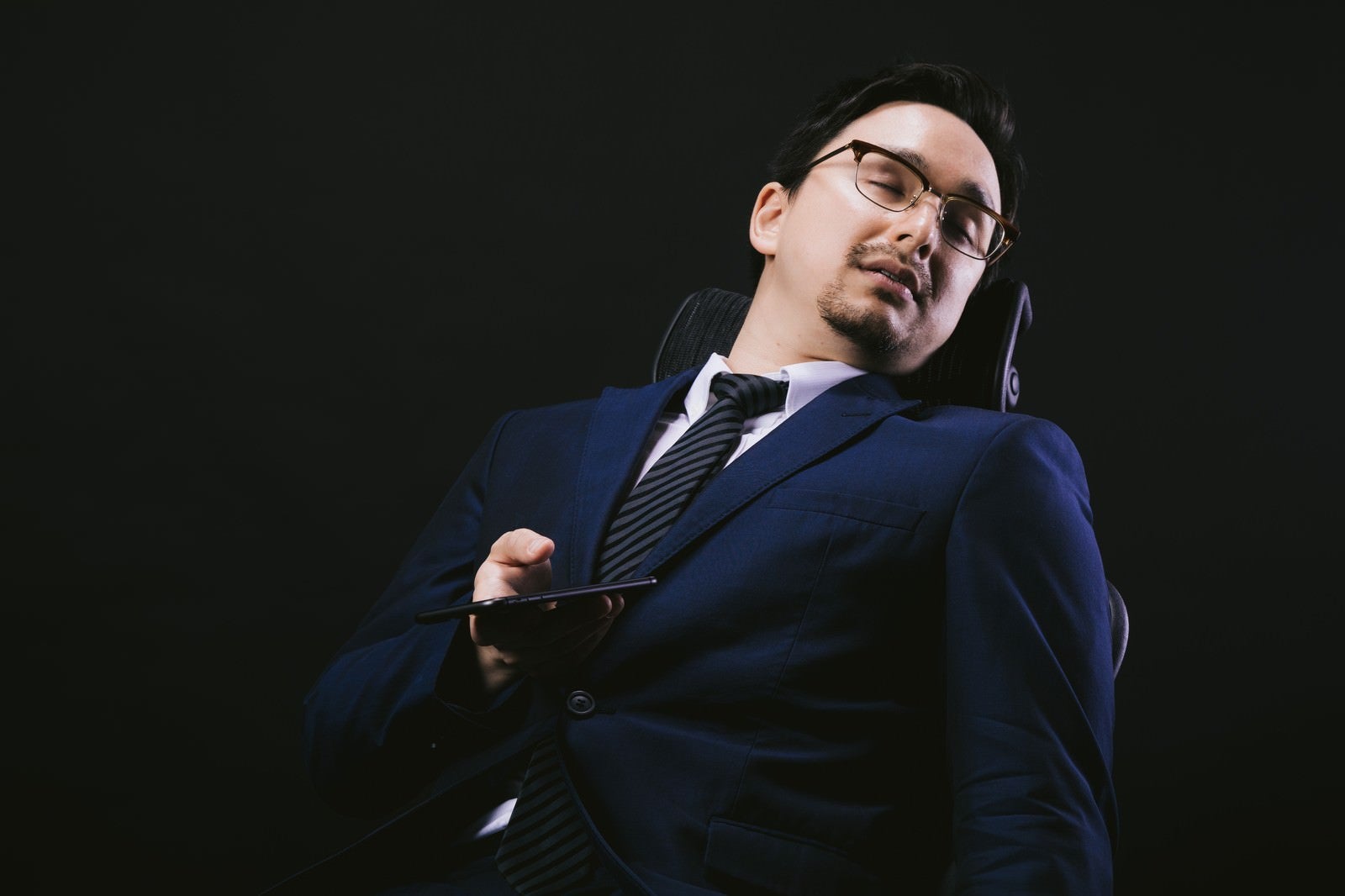 「会社の椅子でスマホやりながら寝落ち」の写真［モデル：Max_Ezaki］