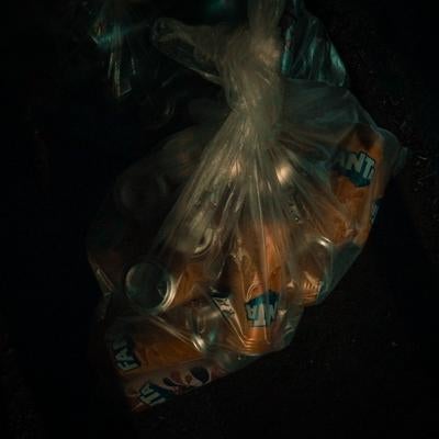 透明なビニール袋に詰められた大量の空き缶の写真