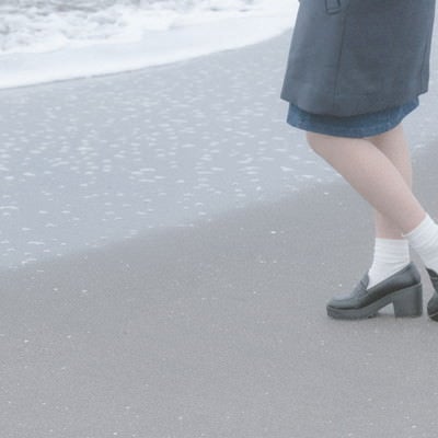 波打ち際でたたずむ女性の足元の写真