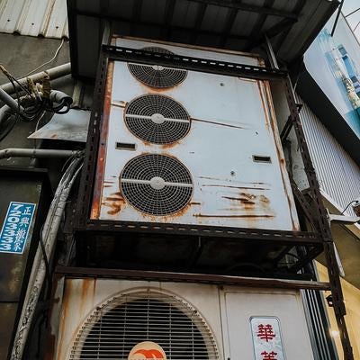 老朽化したビルの壁に設置された業務用エアコンの室外機の素材