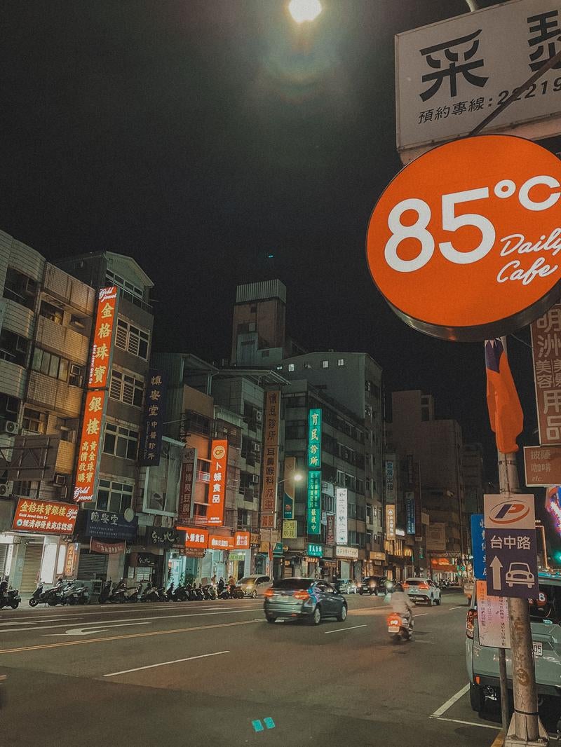 ネオンが輝く通りと85°Cカフェの看板の写真