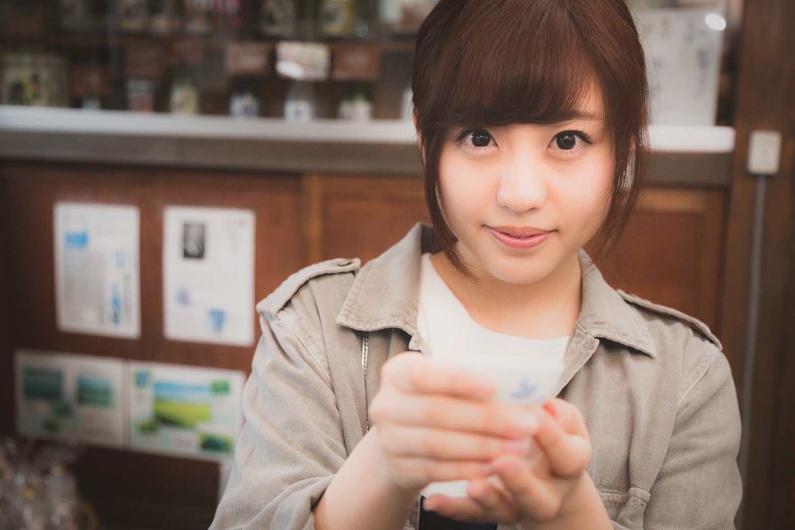 「試飲を勧める日本酒好きの女の子」の写真［モデル：河村友歌］