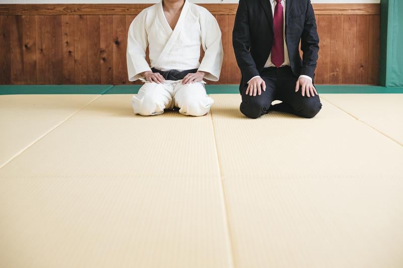 正座する柔道家とスーツ姿の男性の写真