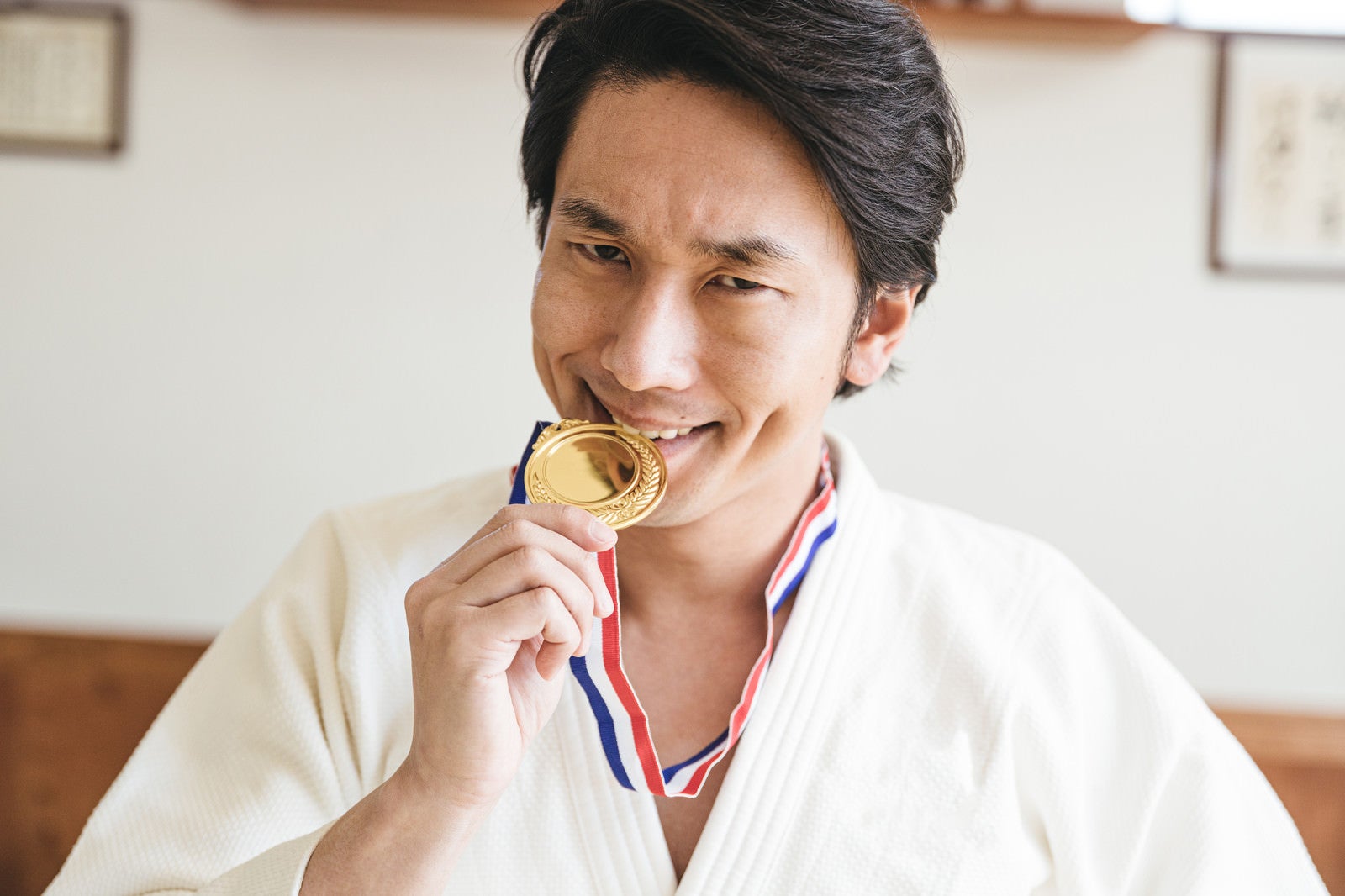 「金メダルを噛む選手」の写真［モデル：大川竜弥］