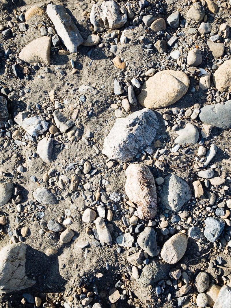 「砂地に残る大中小の石（テクスチャー）」の写真