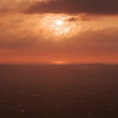 夕暮れに染まる雲間から見える太陽（富山県南砺市）の写真