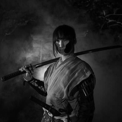 煙の中から登場する刀を担ぐ武士の写真