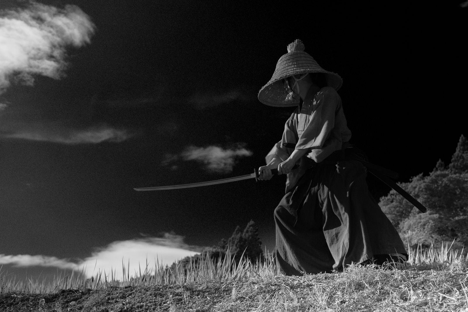 刀を構えて対峙する笠を被った侍のモノクロ写真［モデル：まーこ］