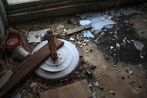割れたガラスやゴミが散らばる廃墟の床の写真