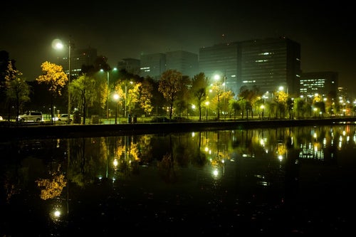 水面に映り込む皇居の堀とビル群の夜景の写真