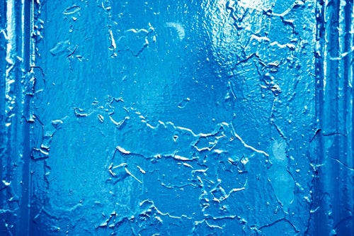 錆びた壁に上から青いペンキを塗るの写真
