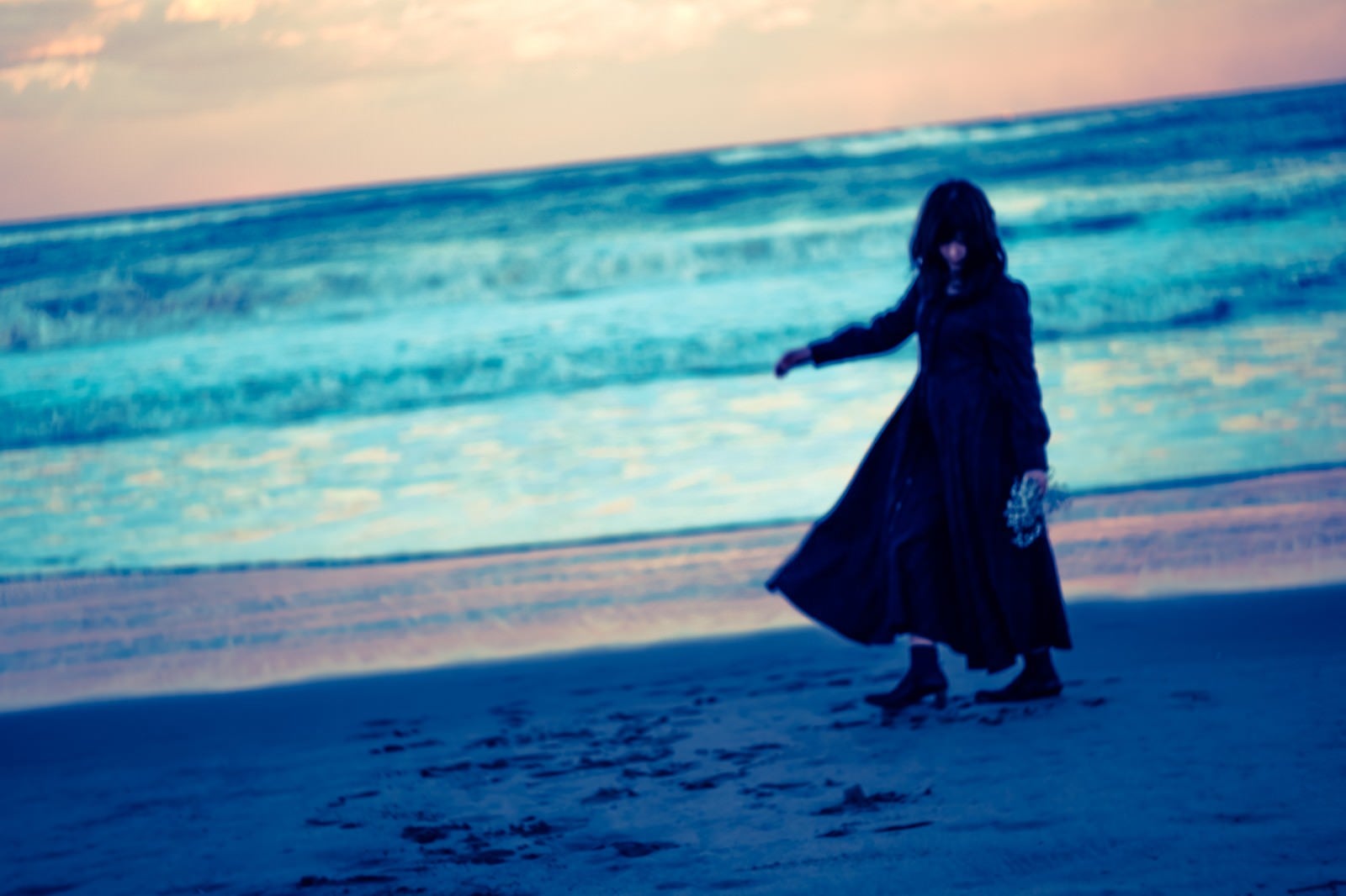 「浜辺を彷徨う黒服の女性」の写真