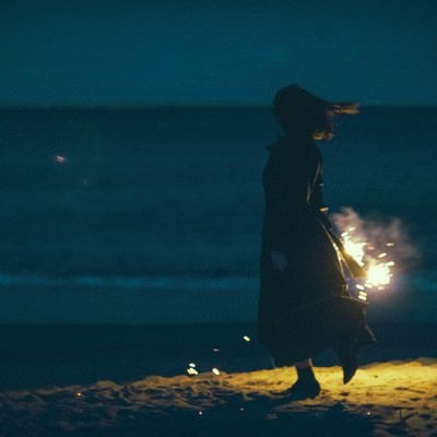 夜の浜辺で手持ち花火と女性のシルエットの写真