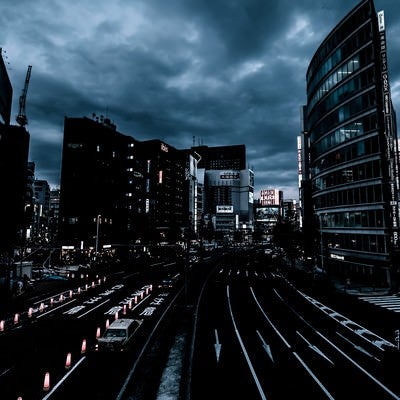 曇り空と日が落ちた新宿駅前の写真