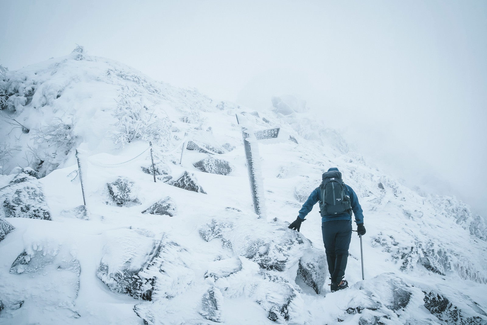 「冬山の標識と登山者」の写真