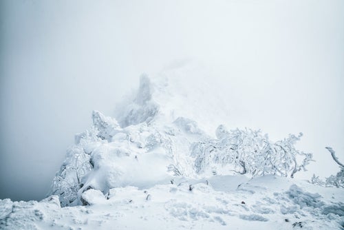 ガスに包まれた稜線と雪景色の写真