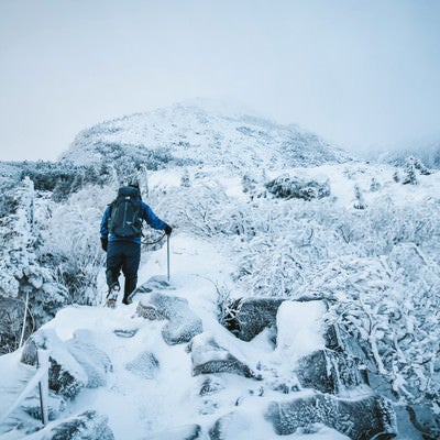 厳冬の登山道で道狭き場所を歩く登山者の写真
