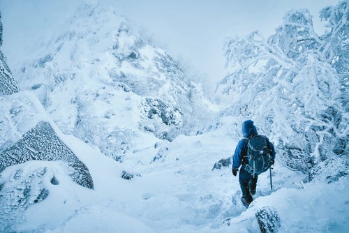 吹雪く雪山を下山する登山者の写真