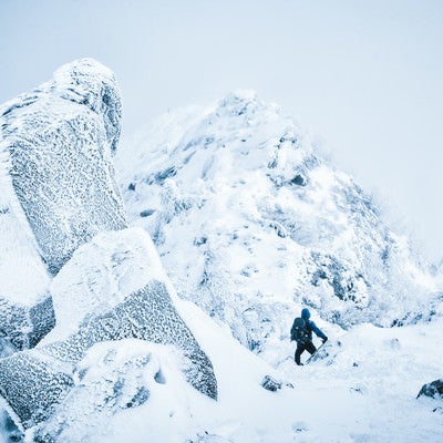 吹雪く天狗岳の稜線と登山者の写真