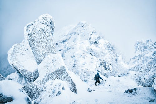 吹雪く天狗岳の稜線と登山者の写真
