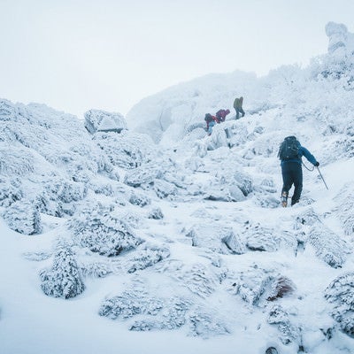 悪天候の雪山に挑む登山者達の写真