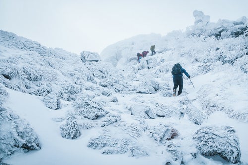 悪天候の雪山に挑む登山者達の写真