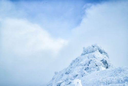 雲の切れ間と積雪した岩峰の写真