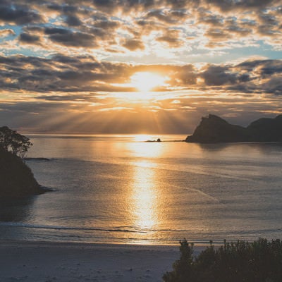 グレートバリア島の海に伸びる朝日のレイライン（ニュージーランド）の写真