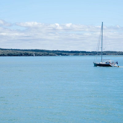 ハウラキ湾に浮かぶ帆を立てていないヨット（ニュージーランド）の写真
