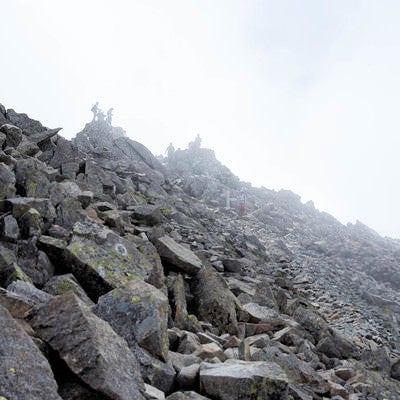 霧のジャンダルムと登山者（奥穂高岳山頂）の写真