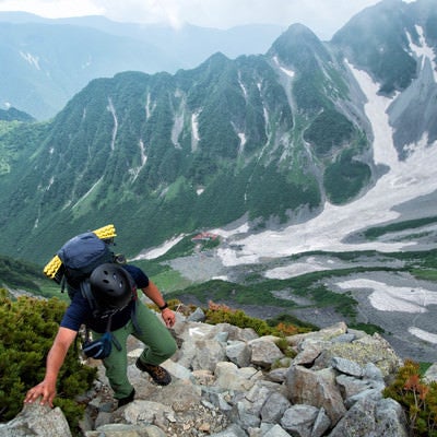 北穂高岳南陵の岩場（崖沿い）を登る登山者の写真