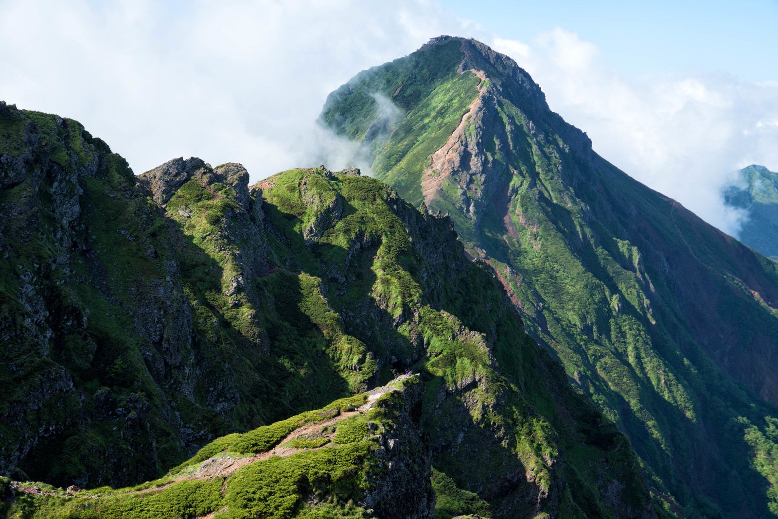 「横岳にある岩場の存在感と赤岳（八ヶ岳）」の写真