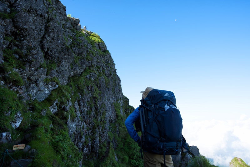 横岳の岩場を見上げる登山者（八ヶ岳）の写真