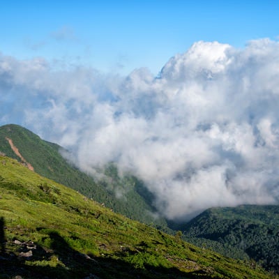 湧き上がってくる積雲と登山者の影の写真