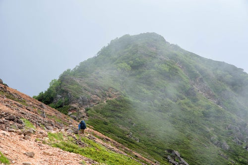 雲に覆われた稜線を歩く登山者の写真