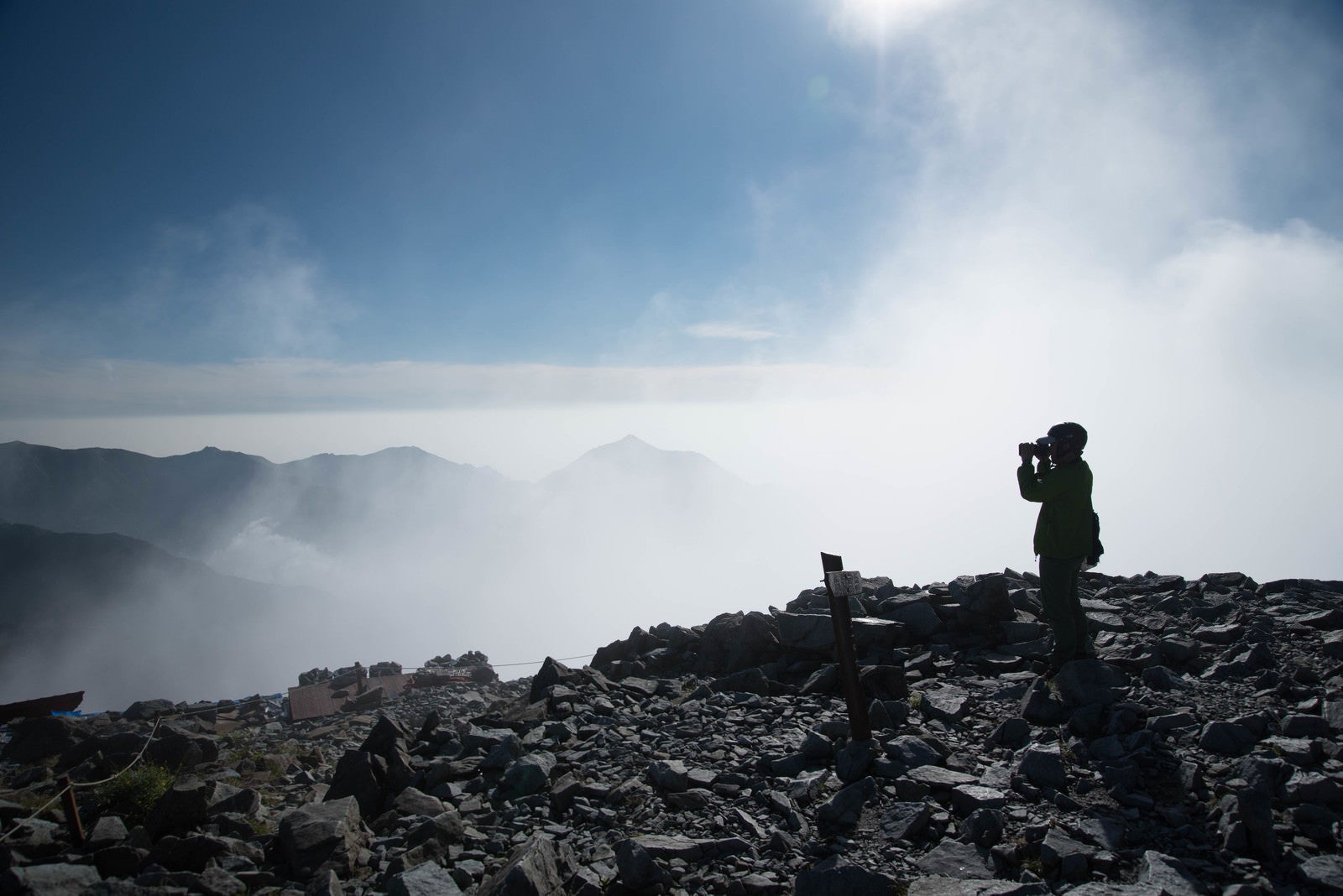 「雲の上の北穂高岳山頂に立つ登山者（北アルプス）」の写真