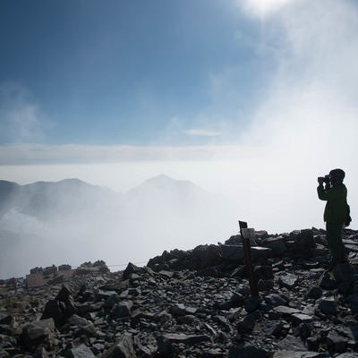 雲の上の北穂高岳山頂に立つ登山者（北アルプス）の写真