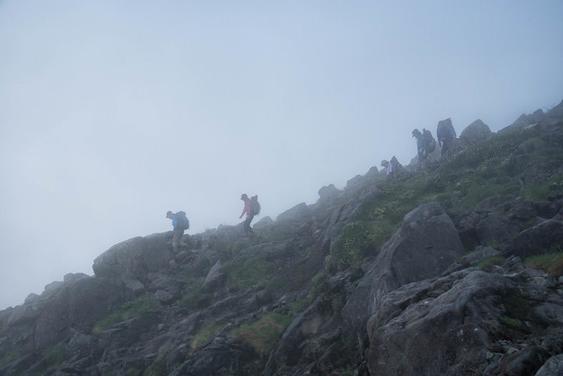 視界不良の霧の中を下山する登山者の写真