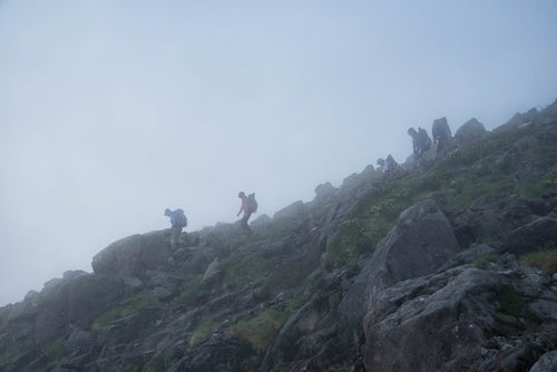視界不良の霧の中を下山する登山者の写真