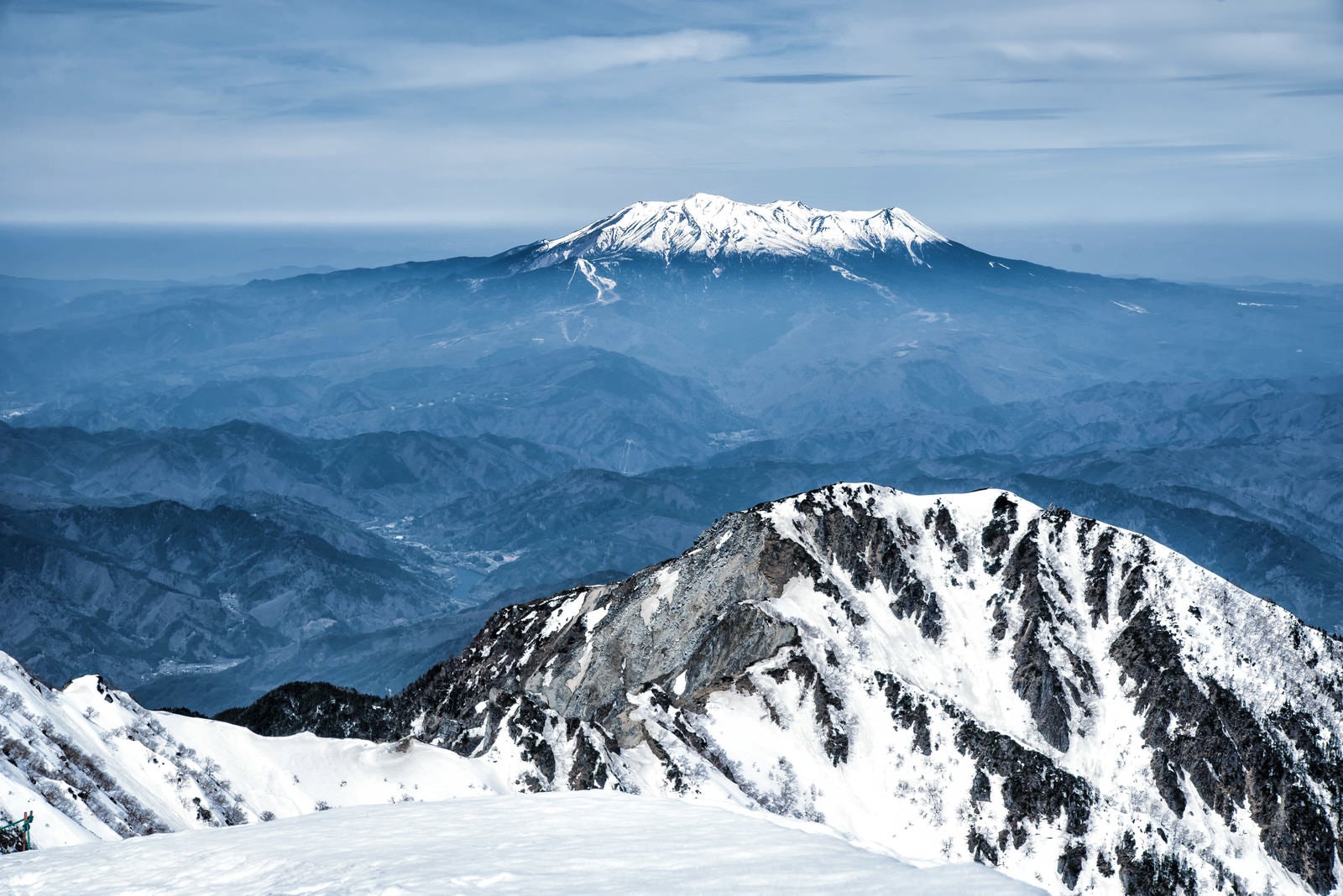 「薄雲から頭を出す御嶽山と木曽前岳」の写真