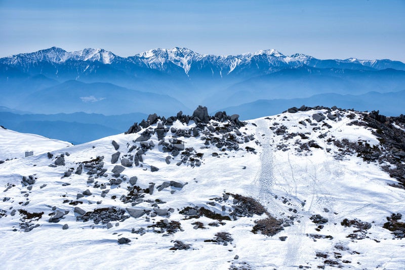 雪残る中岳のガレ場と南アルプスの写真