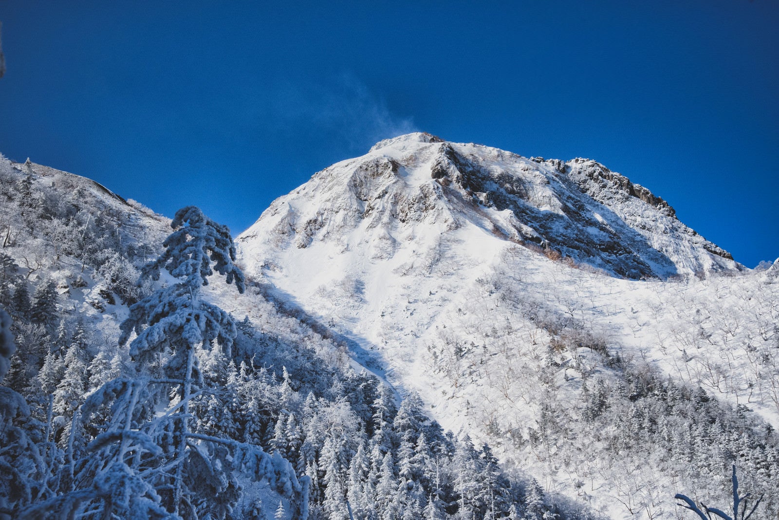 「雪煙の上がる阿弥陀岳（八ヶ岳連峰）」の写真