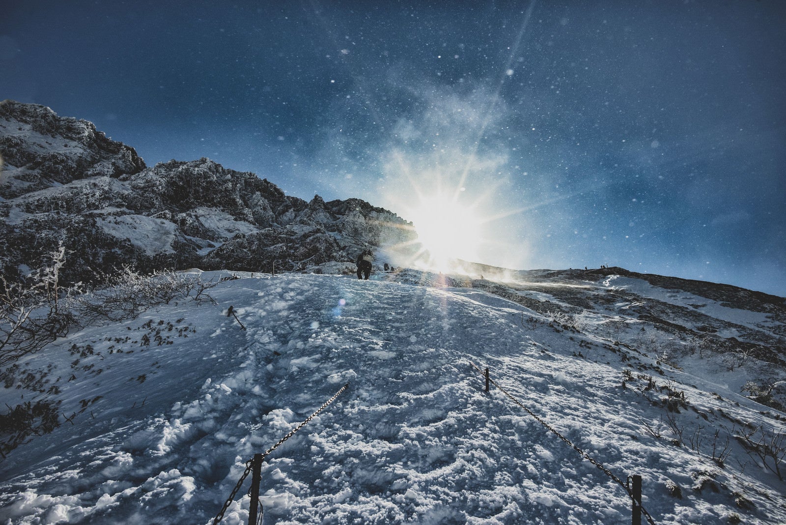 「雪煙舞う稜線と登山者」の写真