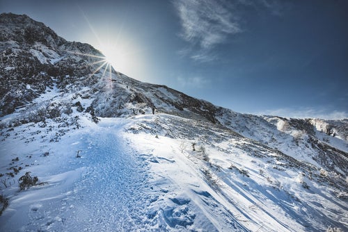 稜線に差し込む光と登山者の写真