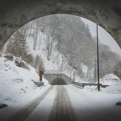 上高地に繋がるトンネルと雪道の写真