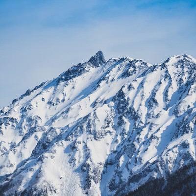 雪化粧の山岳と黒い穂先の写真