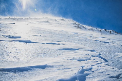 太陽を一面に浴びる雪山の斜面の写真