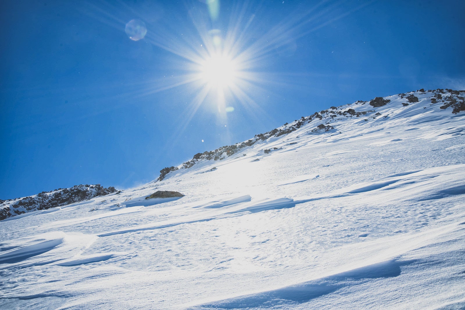「氷化した雪山の斜面と太陽」の写真